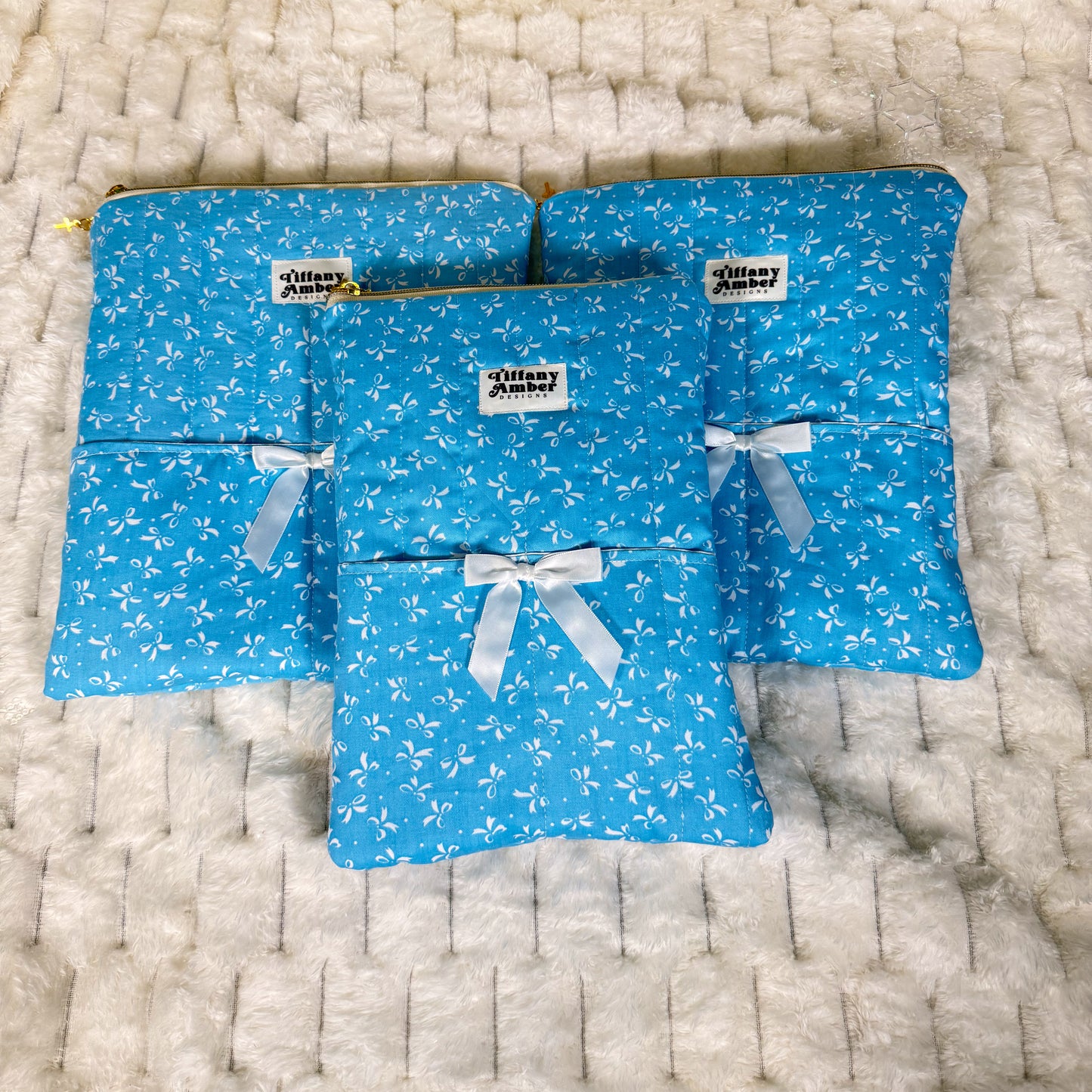 Set of blue pouches with white bow patterns and ribbons on a textured surface